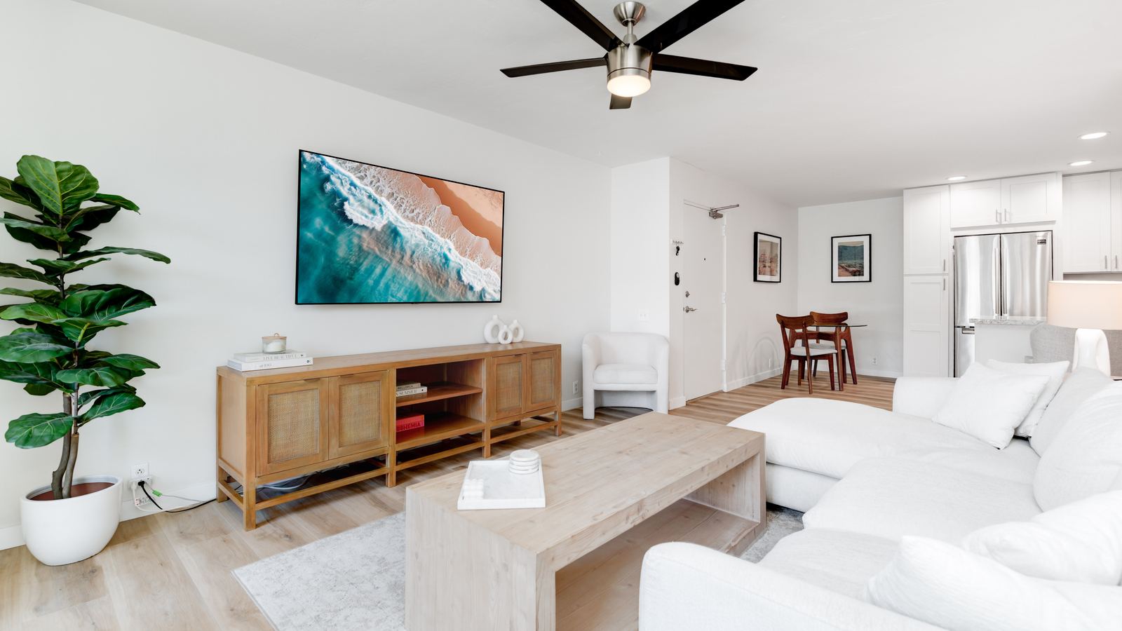 Living room with a white sectional sofa and ocean artwork