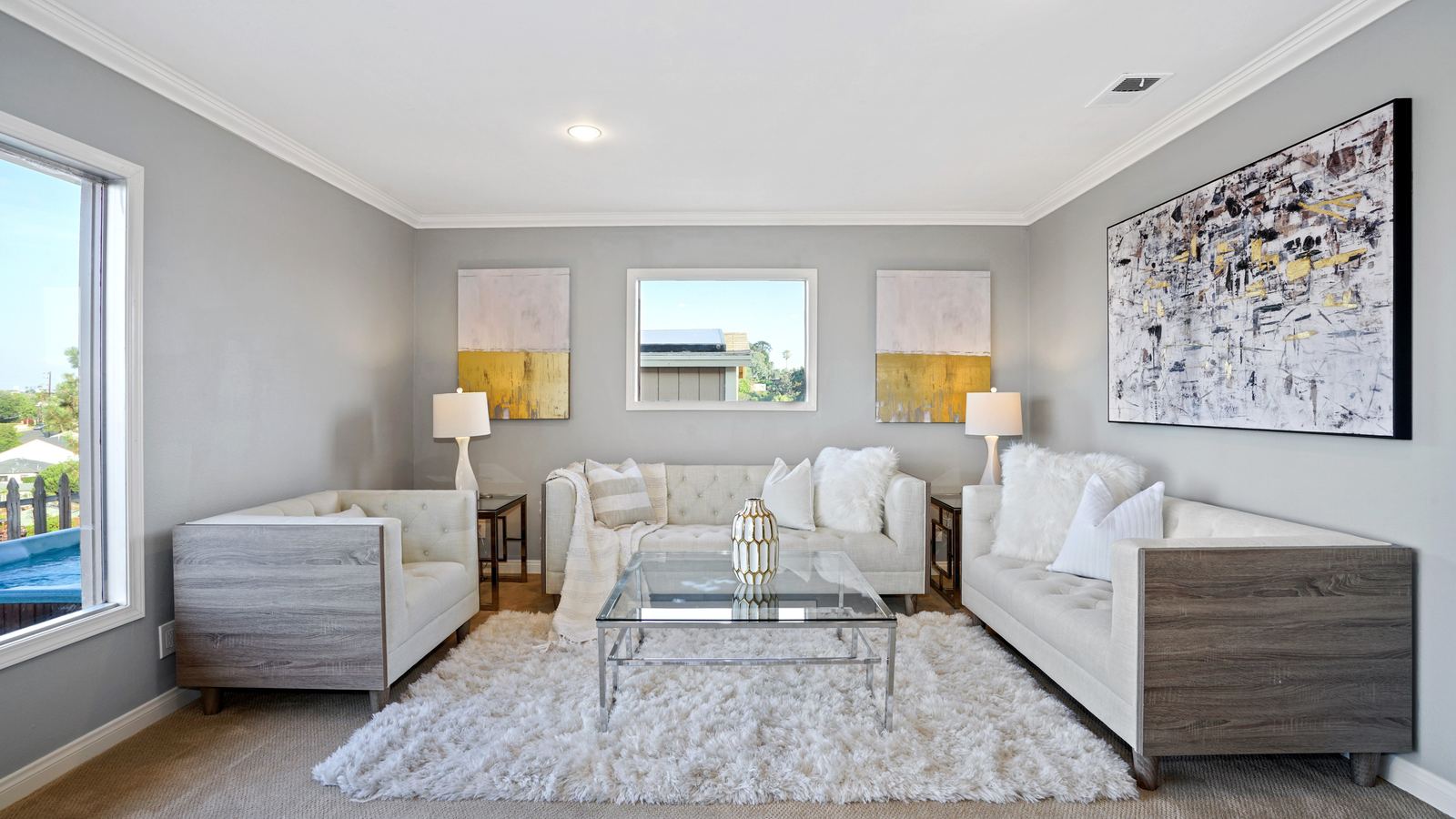 Living room with white sofas, a glass coffee table and abstract art